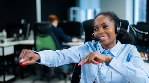 Young african woman talking to a client on a headset. Happy female call center employee