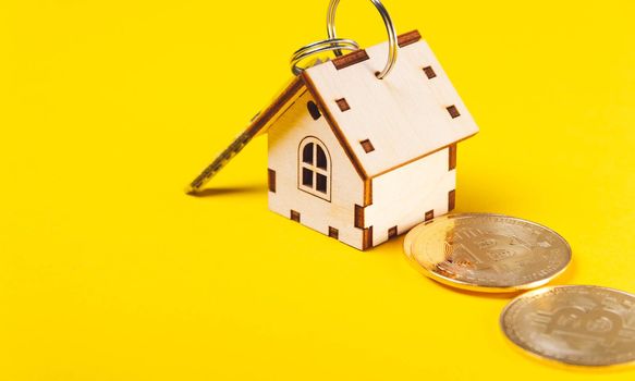 Buying real estate for cryptocurrency. Housing and bitcoins. Coins and house keys. Small wooden house and bitcoin coin.