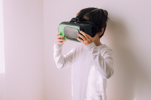 A boy is playing vr glasses on a white copyspace wall . An article about modern gadgets. An article about modern technologies. Place under the text