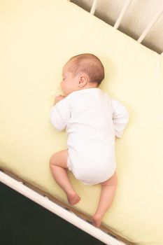 The baby sleeps in the copy space crib . Advertising of children's goods. Illustrating children's articles. A small child. A newborn. A child's dream.