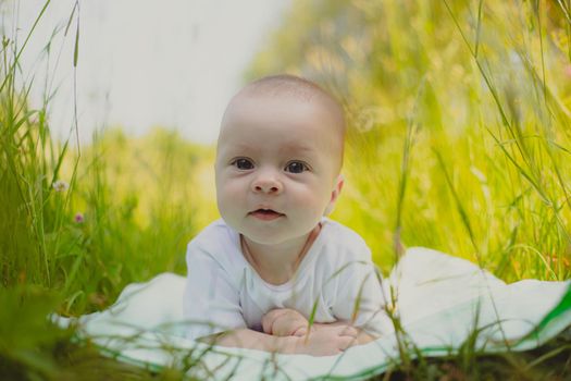 The baby is lying in the grass . A child in nature. Children's article. Copy Space