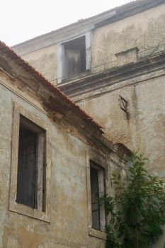 Abandoned building with empty windows during the day in the fog