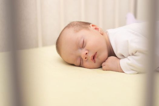 The baby sleeps in the copy space crib . Advertising of children's goods. Illustrating children's articles. A small child. A newborn. A child's dream.