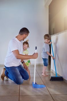 Teamwork gets it done quicker and better. two little siblings helping their father sweep the floor at home