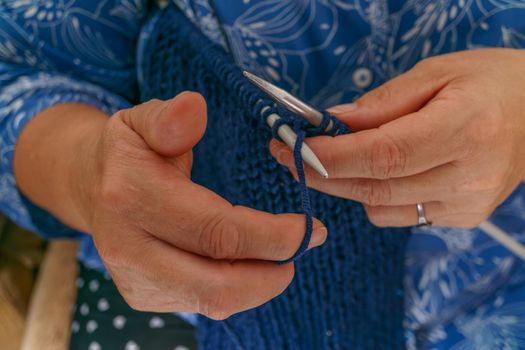 close-up of woman's hands knitting a blue garment
