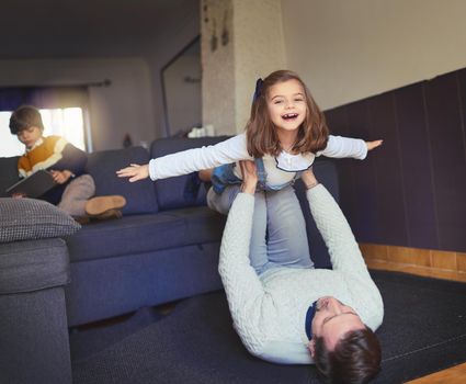 Dont put me down. a man lifting his daughter into mid-air