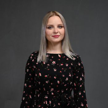 Portrait of a beautiful young blonde woman with long straight hair on a gray background