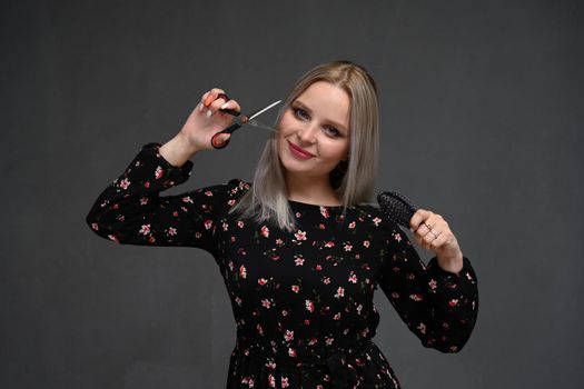 attractive smiling woman portrait on gray background with scissors