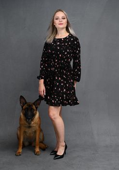 belgian shepherd and woman in front of gray background