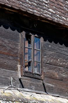 Broken window at an old uninhabited wooden house.