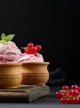 Pink scoops of popsicles with red currants on a black table. Ice cream