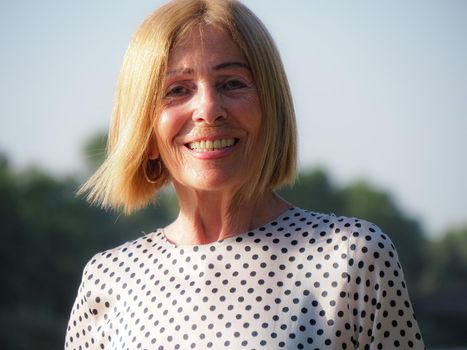 single female pensioner having fun in a park - aging free and wellness concept