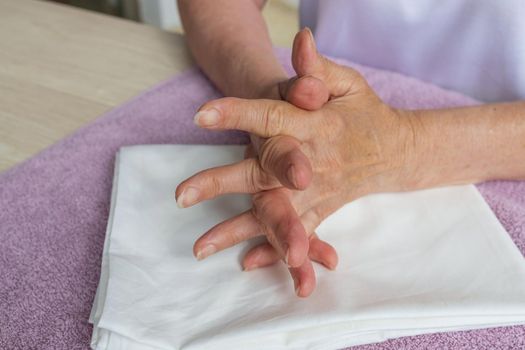 Self-massage of the hands of a Caucasian old woman, massage. Woman crosses her fingers, increases blood flow. Close-up of a man massaging his hand for joint pain, arthritis