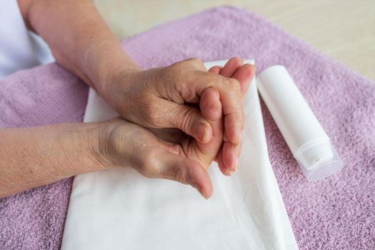 step by step instructions. Close-up, hands of elderly caucasian woman with arthritis. Background white towel, top view, makes himself massage. concept of prevention diseases. Massages her fingers