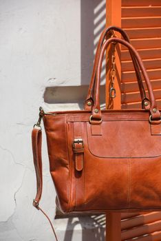 close-up photo of orange leather bag on a wooden blinds. outdoors photo