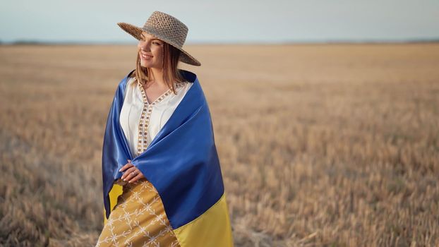 Smiling ukrainian woman with national flag in wheat field after harvesting. Charming rural lady in embroidery vyshyvanka. Ukraine, independence, freedom, patriot symbol, victory in war. quality photo