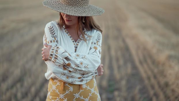 Ukrainian woman in traditional ethnic costume and straw hat in wheat field. Attractive stylish lady in vyshyvanka. Stylish modern girl, Ukraine, independence, freedom, patriot. High quality photo