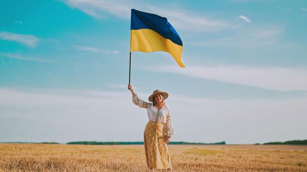 Ukrainian woman waving national flag in wheat field after harvesting. Charming rural lady in embroidery vyshyvanka. Ukraine, independence, freedom, patriot symbol, VICTORY, win in war. quality photo