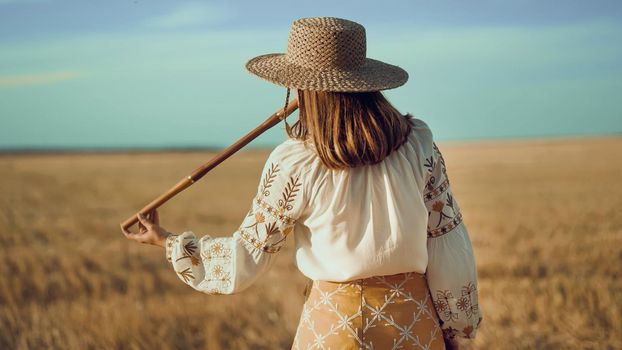 Woman playing on woodwind wooden flute - ukrainian telenka or tylynka outdoors in wheat field. Folk music concept. Musical instrument. Musician in traditional embroidered shirt - Vyshyvanka. photo