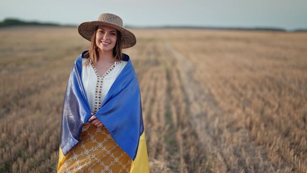 Smiling ukrainian woman with national flag in wheat field after harvesting. Charming rural lady in embroidery vyshyvanka. Ukraine, independence, freedom, patriot symbol, victory in war. quality photo