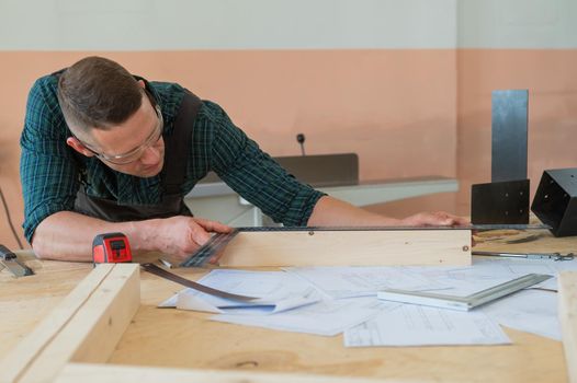 Carpenter measures wooden planks in the workshop