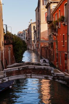 The architectural detail of an old bridge made with red bricks on the typical canal in Venice