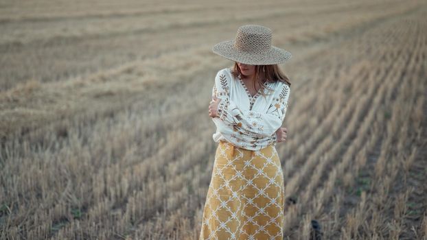 Ukrainian woman in traditional ethnic costume and straw hat in wheat field. Attractive stylish lady in vyshyvanka. Stylish modern girl, Ukraine, independence, freedom, patriot. High quality photo