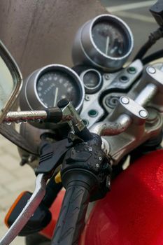 Steering wheel and dashboard of a red classic motorcycle close up