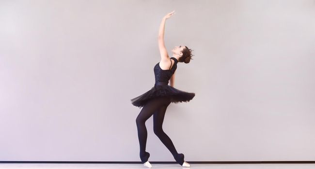 graceful ballerina in black swan dress. Young ballet dancer practicing before performance in black tutu, classical dance studio, copy space