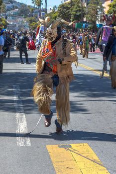 The group is performing a cultural dance with its roots in Spain representing the historic battle between the Moors and the Christians. The dance symbolizes taking the souls of the defeated Moors. The devils wear chaps (called chivarras) made of goat skin and hair, jacket and tie and a wooden mask.