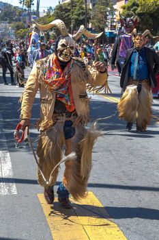 The group is performing a cultural dance with its roots in Spain representing the historic battle between the Moors and the Christians. The dance symbolizes taking the souls of the defeated Moors. The devils wear chaps (called chivarras) made of goat skin and hair, jacket and tie and a wooden mask.