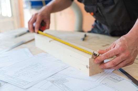 Carpenter measures wooden planks in the workshop