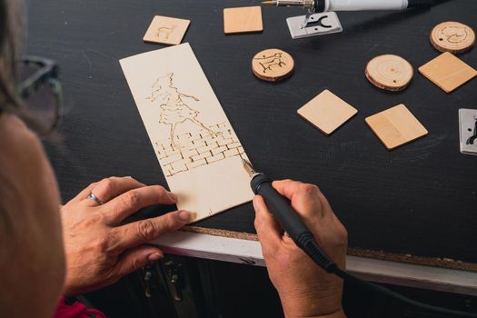 woman drawing with a pyrographer on a wooden table