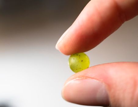 Details and close up of fingers holding green grape.