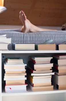 Woman relaxing on the couch against books on the shelf at home.