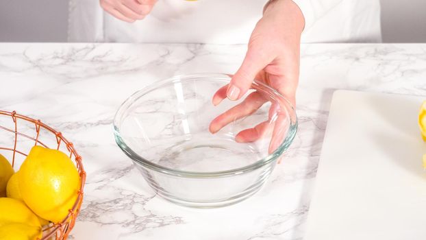 Step by step. Squeezing fresh lemon juice into a small glass mixing bowl.