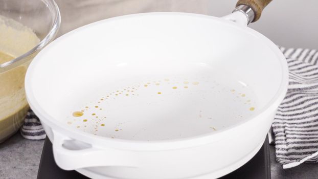 Step by step. Frying pumpkin pancakes batter on a white frying pan.