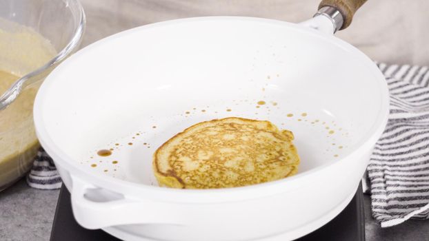 Step by step. Frying pumpkin pancakes batter on a white frying pan.