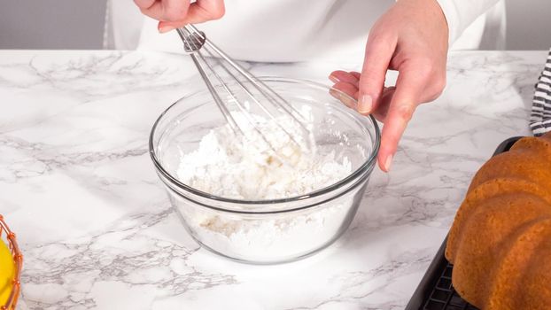 Step by step. Mixing ingredients in a glass mixing bowl to prepare lemon glaze for a lemon bundt cake.