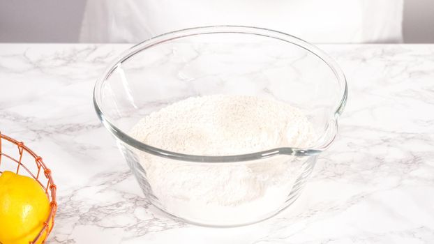 Step by step. Mixing ingredients in a glass mixing bowl to prepare lemon bundt cake.