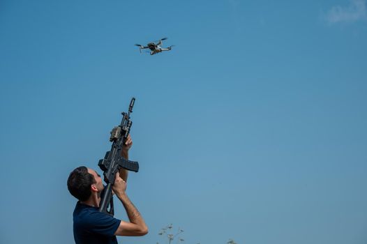 Caucasian man shoots a flying drone with a rifle