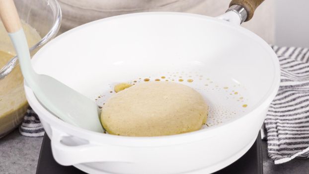 Step by step. Frying pumpkin pancakes batter on a white frying pan.