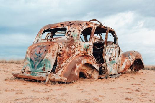 A vintage car sits abandoned and rusting in the harsh elements of Australian outback. Many rusted cars and other vehicles left behind can be found in journeys of the outback.