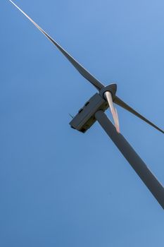 Panoramic view of wind farm or wind park, with turbines for generation electricity on sunny summer day. Green energy concept. Eco renewable energy power. Close up