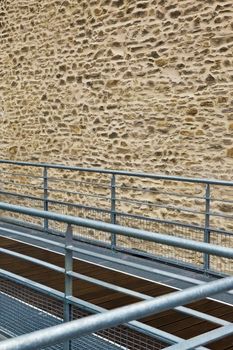 Wooden and metal walkway and stone wall in the background