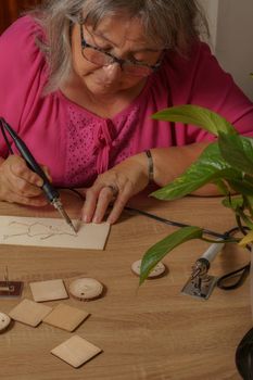 woman drawing with a pyrographer on a wooden table