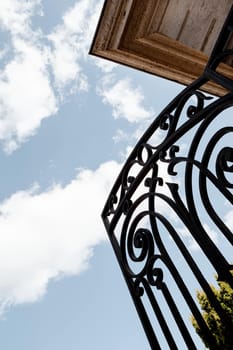 Open wrought iron gate and blue sky on background