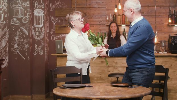 Senior man with flowers for his wife. Romantic couple. Senior couple in their sixties.