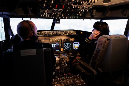 Team of airliner and captain using power switch on cabin dashboard to fly aircraft jet. Aircrew people pushing buttons on control panel command to travel with airplane, navigation radar.