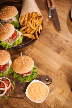 Top view of burgers with lettuce on a wooden table. Chef knife.